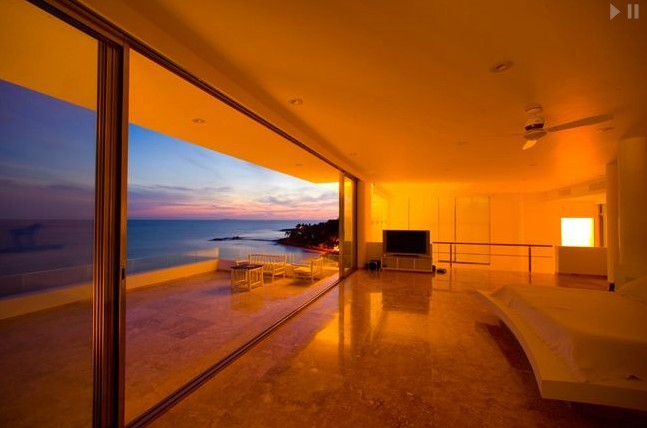 The floor-to-ceiling sliding glass doors offer breathtaking views of exquisite, blue seas.