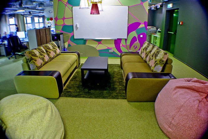 A comfortable and colorful living room serves as an unofficial meeting spot for employees and even features a drawing board.