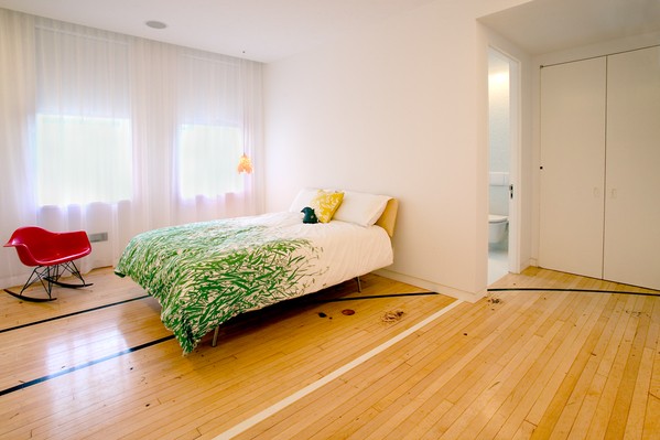 "The Apartment" group wanted to retain some of elements of the old basketball court, and so decided to keep the basketball court flooring in the private areas of the house, such as this bedroom.