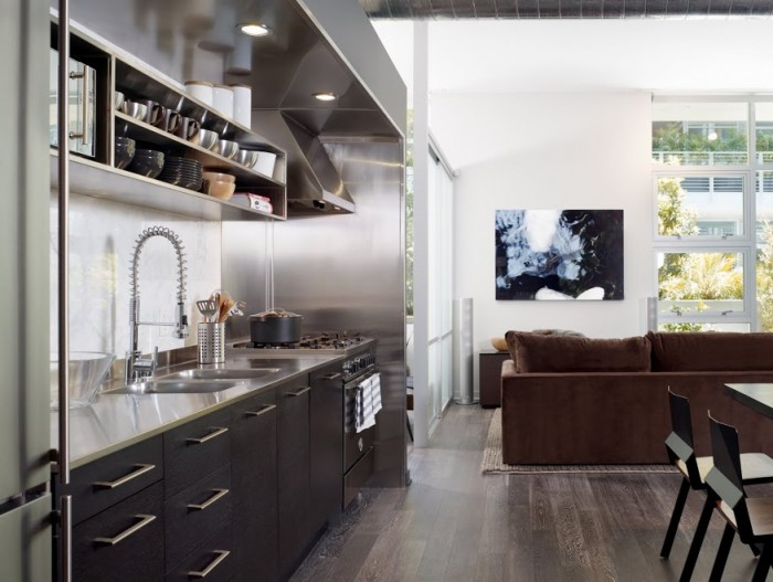 The young single male's open floor plan kitchen/dining/living space gets a shot of high dose of masculinity with industrial strength materials such as stainless steel, graphite cabinets and rustic wood floors.