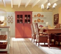 A pumpkin-hued china amoire adds a punch of color to this gorgeous old world style eat-in kitchen. It is certainly warm and cozy and feels like fall.