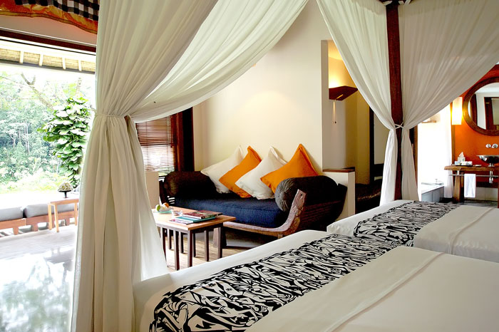The bedroom in one of the deluxe villas boasts a wall open to the outdoor and furnished in traditional Indonesian decor.