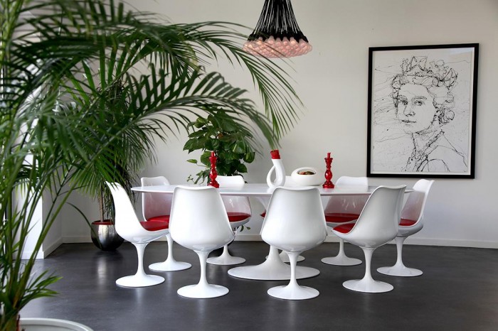 A large tulip style modern table and chair set creates a welcoming place to gather with family and friends over a nice meal.