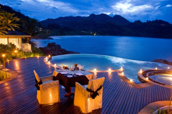 dining by round infinity pool overlooking ocean cliffs