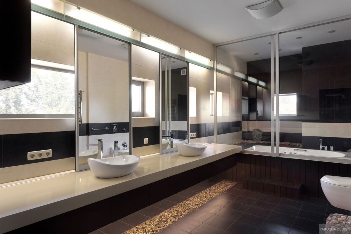 his and hers twin sinks in modern mirrored bathroom with large tub