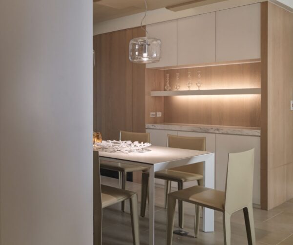 A built in cabinet, fitted with backlights and a marble counter, adds elegance to the space between kitchen and living area.