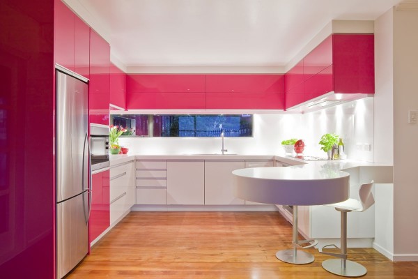 A window backsplash adds extra brightness to this dynamic pink modern kitchen.