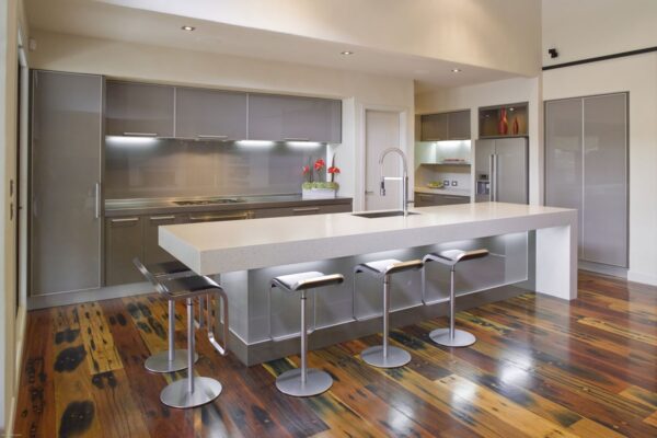 Warm wood plank flooring and plentiful light provide the perfect canvas for colder metal elements found in this modern kitchen.