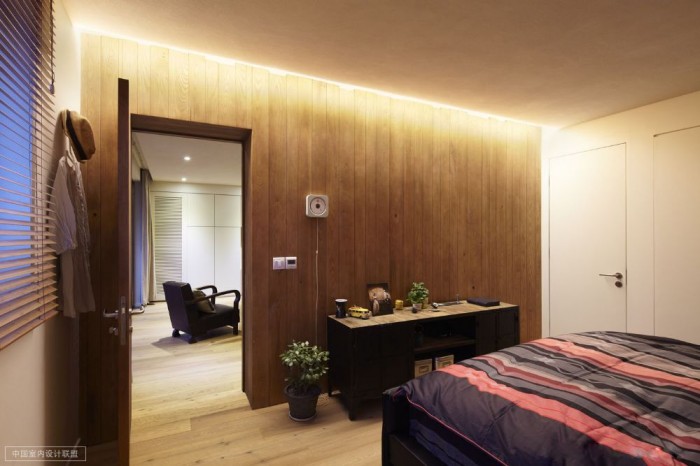 simple bedroom warm wooden cladding and occasional chest topped and flanked with jade plant