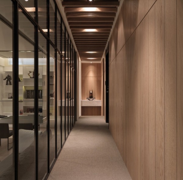 The long hallway stretches the length of the living and dining spaces and is enclosed by a smoky glass wall.