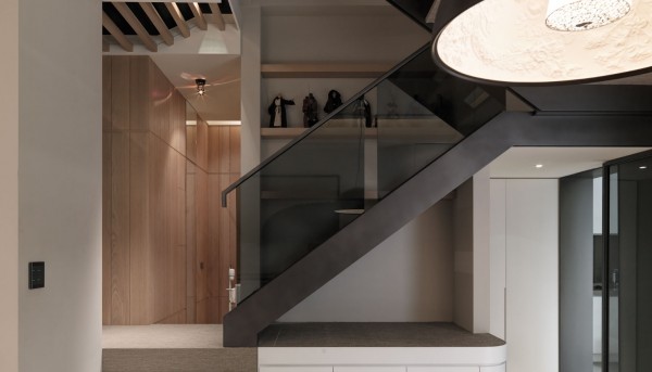 The staircase boasts a smoky glass railing framed in steel with display shelves in backdrop.