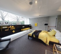 yellow and grey bedroom with fitted storage and black leather armchair