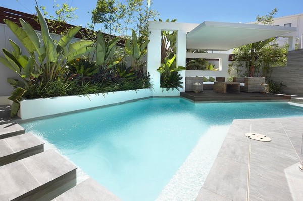 Custom Pool Area- white covered outdoor lounge patio with stepping platforms and palms