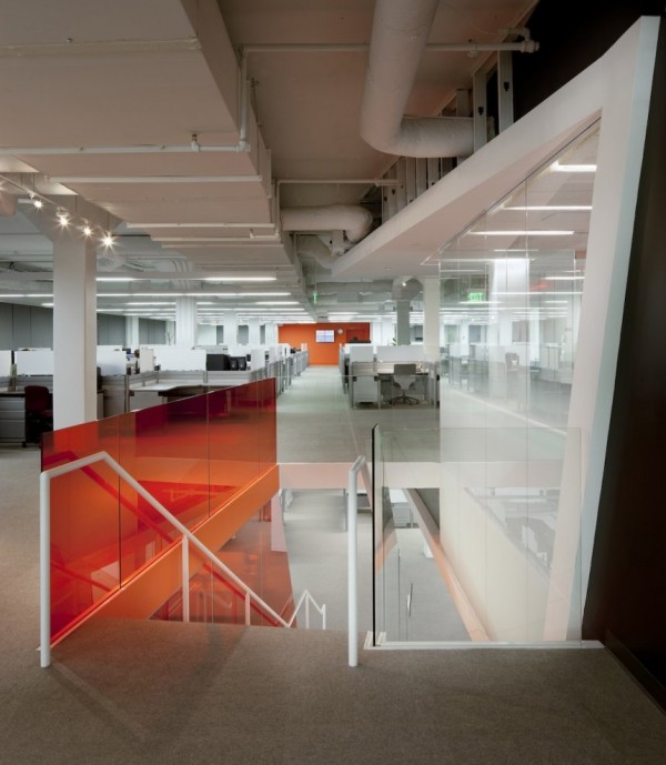 Kayak Startup Tech Office- glass panelled stairwell with view to open plan white and orange work stations