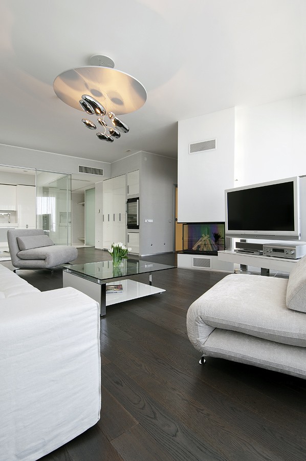 Living with neutral soft furnishings modern lighting dark wood flooring and view to glass kitchen portrait