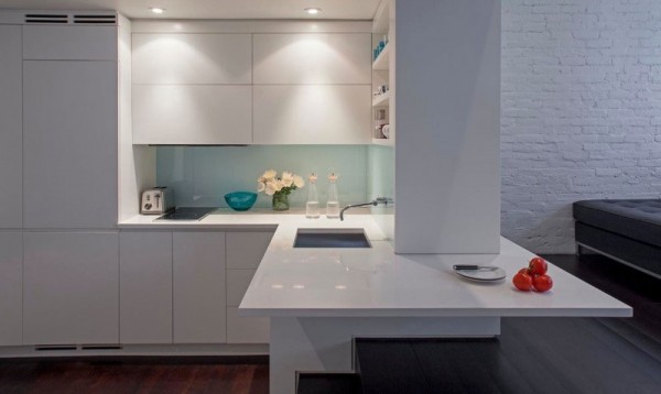 The resident is greeted by a compact corner kitchen. Down-lit and coated in a glossy white lacquer, it successfully conveys a modern yet simple aesthetic, which is particularly important in smaller spaces.