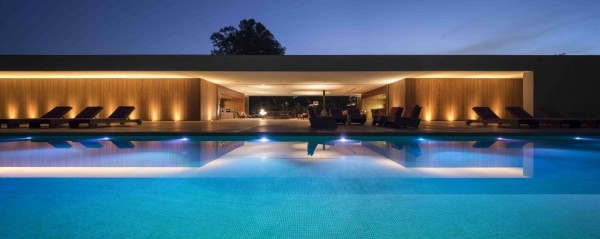 Marcio Kogan's Casa Lee Concrete House- view from illuminated pool to exterior at dusk