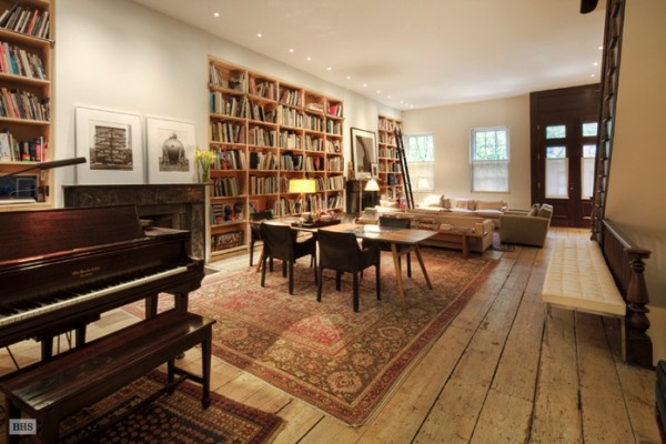 The main living space is warm and inviting with a brightly-hued oriental rug, a richly finished baby grand piano and built-in bookshelves.