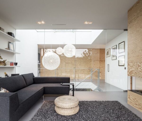 Gorgeous globe lights made of string illuminate the stairwell beyond the living room. The modern sofa adds texture to the space with rough wool upholstery as does the deep pile shag rug in shades of gray.