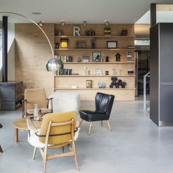 A seating area of modern designer chairs with arch chrome lamp chiming in from above over a round coffee table.