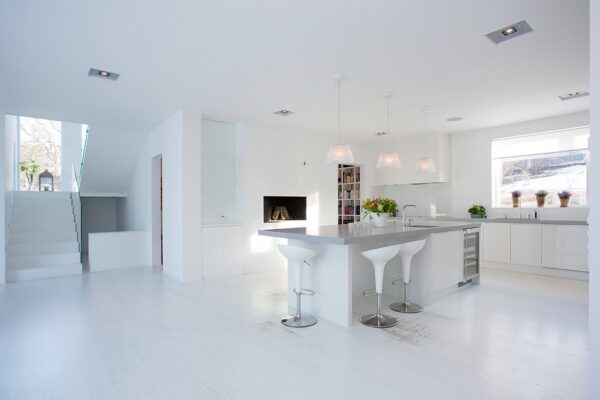 The brilliant white kitchen has a nice size island with bar seating as an eat-in feature. Painted white wood floors bounce the light throughout the space.