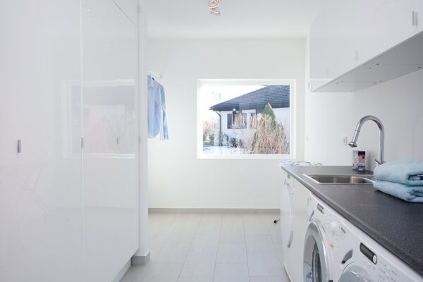 A nice size laundry room features plenty of built-in behind door storage and built-in washer and dryer within the cabinetry.