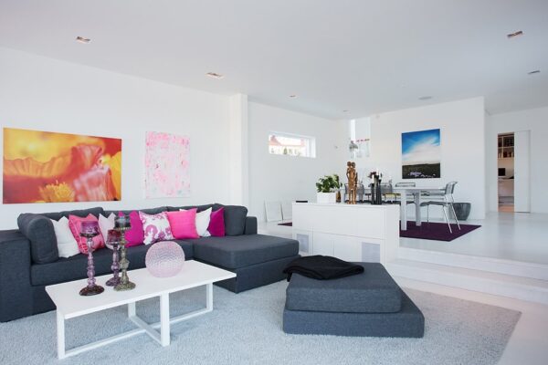 A contemporary open living space boasts a comfy grey flannel sectional in the living area and a table and chairs for six in the dining area. A small window above the table allows for extra natural light.