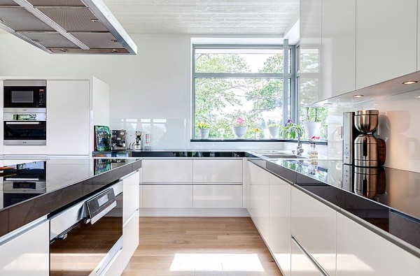The kitchen is all about function in a sleek modern package. The black glass cabinet tops contrast nicely with the pure white space.