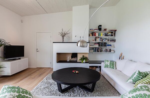 The villa's living room mixes modern with traditional elements. A small fireplace with modern surround sits at the far wall. Contemporary toss pillows add pattern and color to the space.