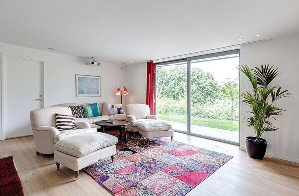 Modern Villa Living Room 4 A media room is decorated in an English style with comfy armchairs and ottomans in white and beautiful patchwork rug added for interest and texture.