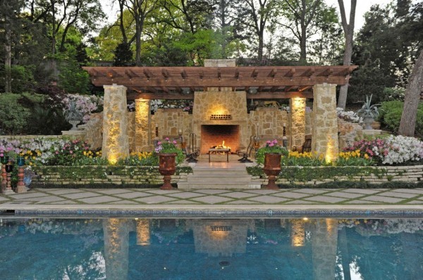 Pools and water features have long been a central element in outdoor living spaces. This one offers a cool element contrasting with the warmth of the fire and lighting in the living area beyond.