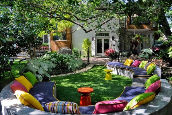 Vivid color is the order of the day in this unusual garden space with curving bench-like seating filled with brightly-hued textiles and plentiful toss pillows.