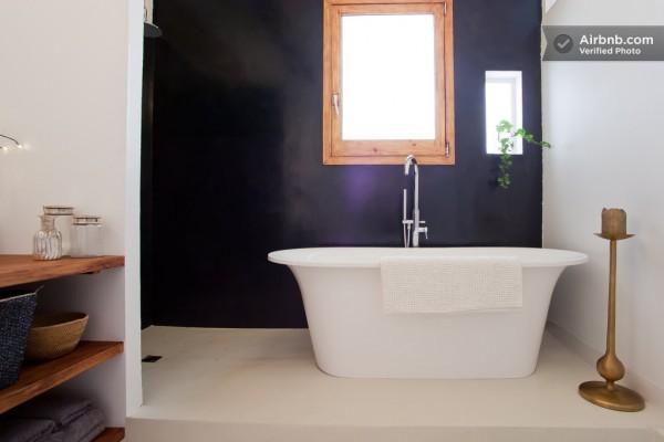 A large soaking tub takes center stage in front of a dramatic black wall.