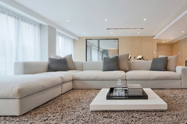 An oversize white linen sectional takes center stage in this open space living/dining space. An unusually low coffee table sits on a deep pile area rug.
