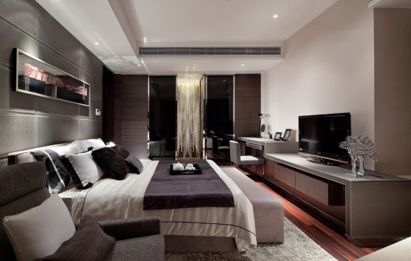 Rich colors mixed with crisp white and mid-tone neutrals provide a luxurious yet relaxed feel in this master bedroom suite. A gorgeous waterfall chandelier hangs in the background.