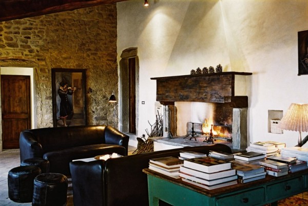 A manor house cannot be complete without a fireplace of course, and Casa Bramasole is not lacking in that respect. The exposed brick is a great backdrop for the main living area which also features leather couches and an antique desk loaded with books.