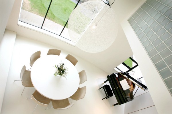 An enormous string globe light fixture echoes the large round table below while a baby grand piano sits tucked into a corner of the open space living area.