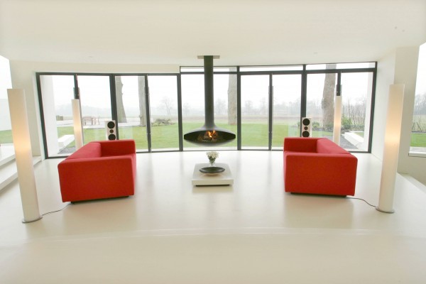 Twin vivid red sofas arranged symmetrically in between four identical floor lamps with suspended fireplace in the center.