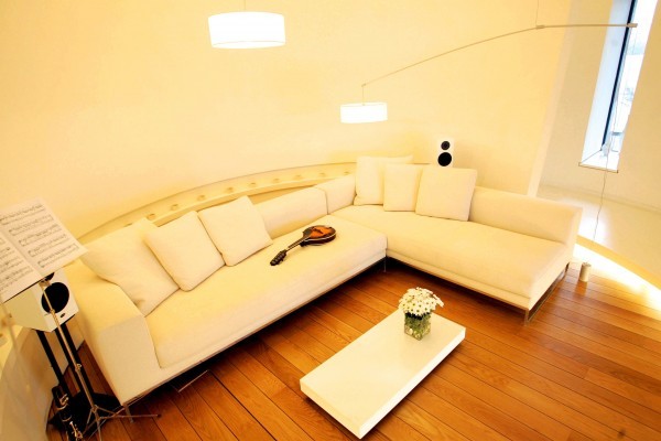 A music room sits in one of the circular rooms of the tower itself. A cream-colored modern sectional provides ample seating in the tiny space.