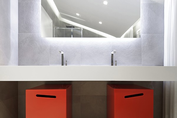 Red storage bins offer the only pop of color in the white bathroom.
