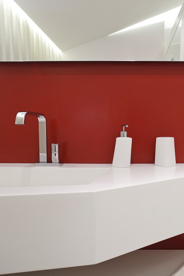 The guest bathroom gets a splash of color from a brick red wall amping the liveliness of the space.