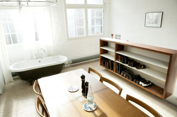 The next big space saving tactic employed in this home is a second combination space which makes up the kitchen, dining room and the bathroom. This may seem strange, but it actually works in this space. A full stand in tub was added against the wall, right next to a wall of windows and the shower curtain is also suspended from the ceiling and surrounds the entire tub for privacy. Because it is off to the side, it doesn’t grab your attention immediately and it doesn’t become the focal point of the room. Built in shelves make a great place for shoe storage and hidden cubbies in the wall hide the garbage can and a small refrigerator.