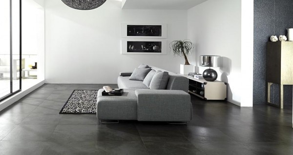 These dark stone tile floors create contrast with the bright white walls and gray furnishings. The design is clean and stylish.