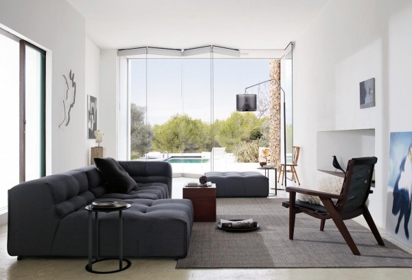 Dark gray fabrics and cherry wood finishes complete this space. It is comfortable yet stylish, and has natural touches exemplified by the retractable glass doors which open to the outside.