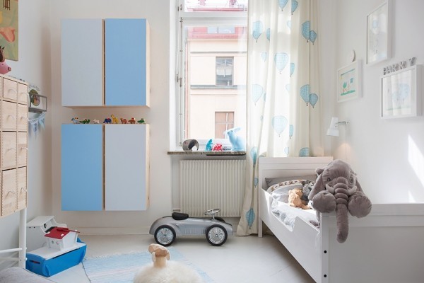 For a growing family who is not afraid of some stains, the children's room is also replete with whites and blues, including practical built-in cabinetry for storage and gauzy, adorable curtains decorated with baby blue balloons.