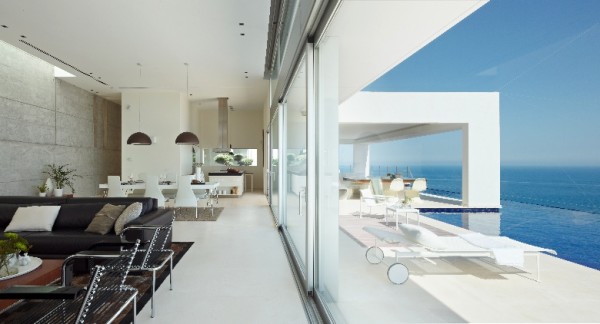 The white also acts as a reflective surface for the many sources of light that have been included in the modern design. Not only does sunlight flood in from the floor-to-ceiling windows that face the sea, but a unique skylight crowns the living area's concrete accent wall, letting sun in from above as well. At night, soft lighting from many hanging fixtures bring necessary visibility without harshness.