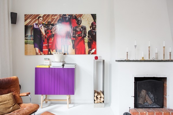 Although most of the walls in the apartment are a shockingly clean white, the designer brings in many colorful elements that pop in the sun. This bright violet cabinet cannot be ignored, even as it is flanked by a deliciously worn leather chair/ottoman combination and a built-in fireplace.