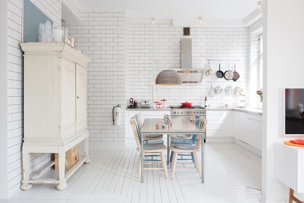 The kitchen and dining area bring the white theme to new heights with white tiled walls and greyish white marble countertops. A funky silvery light fixture is an interesting design focal point, even when its bulbs are unnecessary.