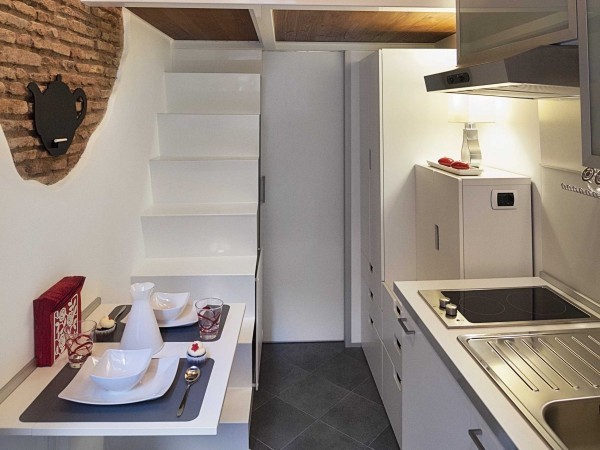 A dining table that can seat up to four people folds out from the wall and can easily be stowed away when not in use. Exposed brick from the original structure give the kitchen area a feeling of a cozy corner café.