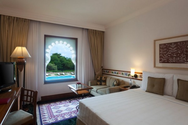 The rooms are distinctly Indian in their design as well. In this particular guest room, an elegantly arched window looks out onto one of the hotel pools. Local rugs and artwork bring the culture of the region into the room as well.